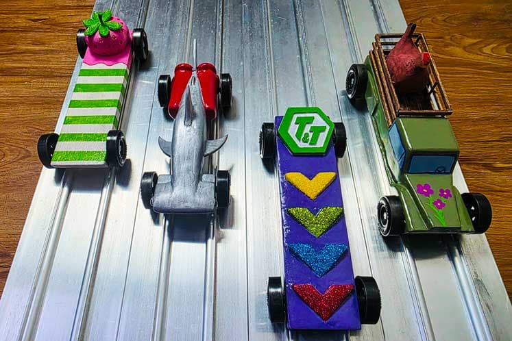 Pinewood derby cars lined up on the starting block